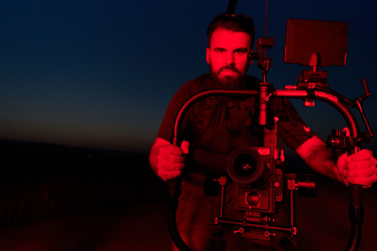 A skilled videographer captures the intensity of athletes running, illuminated by vibrant red lights, encapsulating the energy and determination of their nighttime training session.