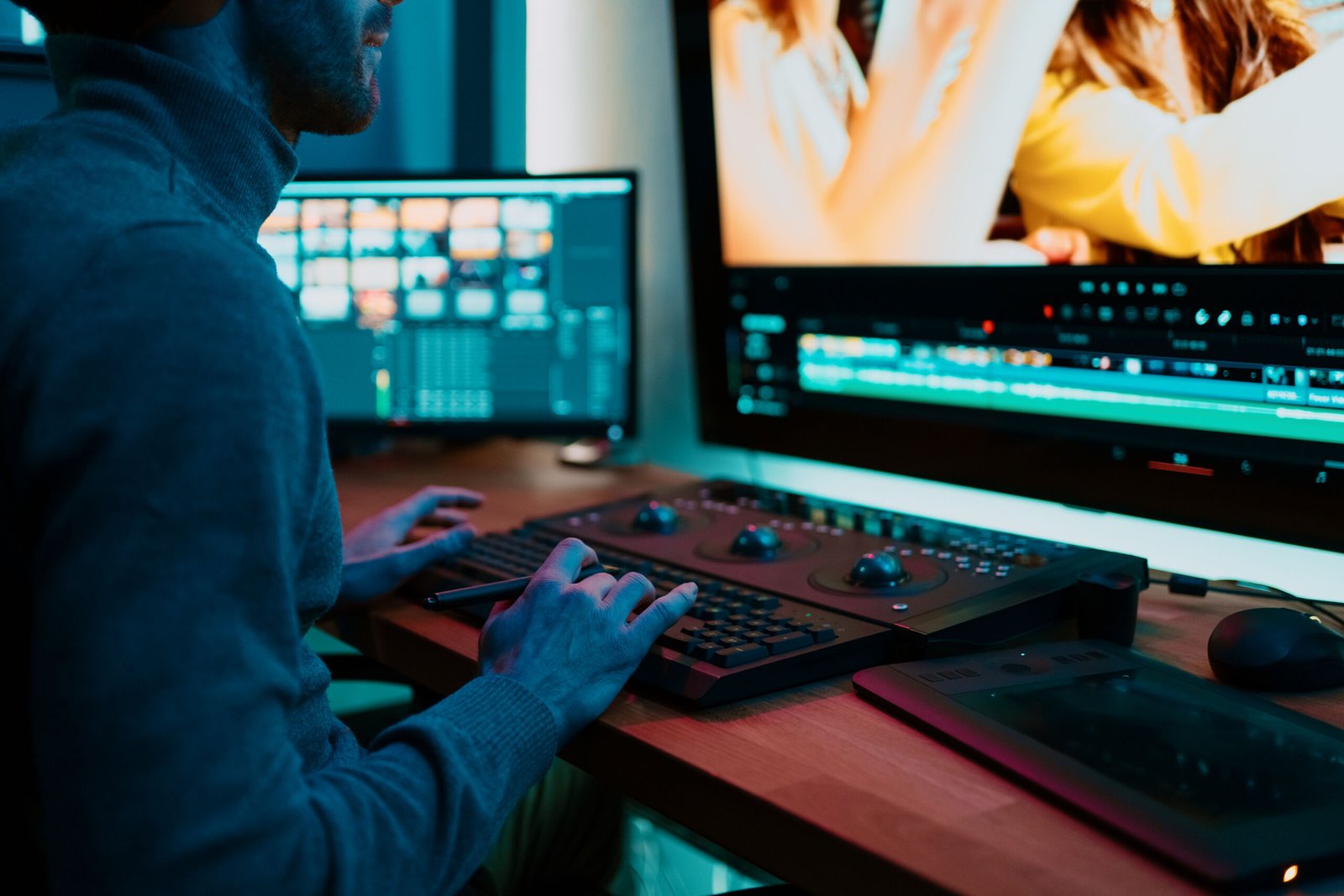 Attractive Male Video Editor Works with Footage or Video on His Personal Computer, he Works in Creative Office Studio or home. Neon lights